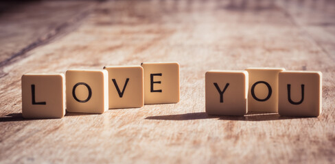 Love you word made of tiles on dark wooden background