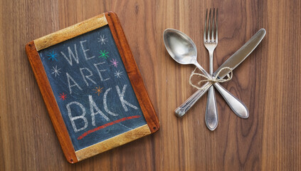 Restaurant blackboard announcing reopening after the corona lockdown,cutlery and blackboard,food...