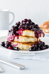 Fluffy pancake stack topped with warm blueberry sauce ready for eating.