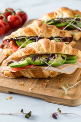 Fresh croissant sandwiches on a wooden board ready for eating.