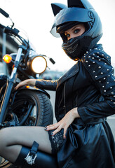 A beautiful girl in a motorcycle helmet sits near a bike.