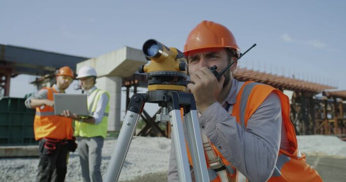 Male surveyors using theodolite together