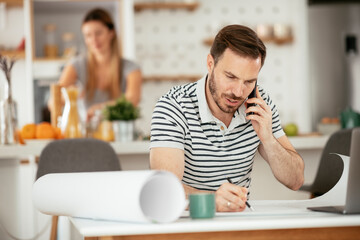 Young man working and talking to the phone. Handsome man working at home...