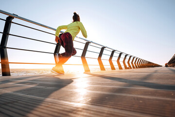 outdoor workout concept. young woman in tracksuit performs sports workout on the pier