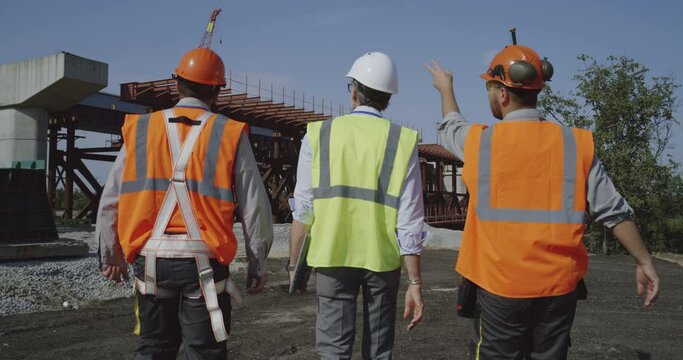 Professional engineers walking towards unfinished bridge