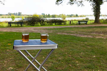 Fototapeta premium two glasses of tea outside on a table on the river Maas