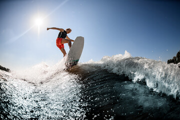 Active man rides on surf style wakeboard on the wave