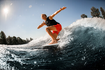 Close-up of man riding down the wave on surf style wakeboard on sunny day