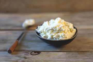 Fresh mascarpone cheese in a bowl on a wooden surface. Selective focus. Macro.