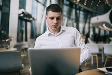 Focused male freelancer watching laptop during work in cafeteria