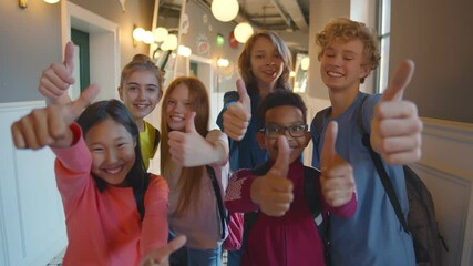 Happy diverse kids students with thumbs up at school