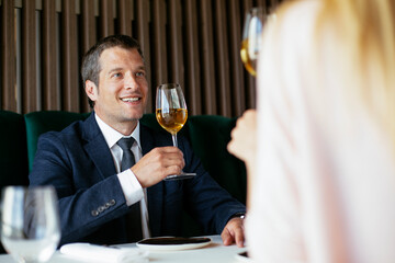 Handsome businessman dressed in the suit drinking wine. Businessman enjoying in the restaurant..