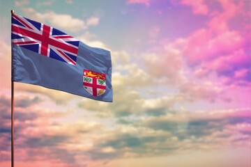 Fluttering Fiji flag mockup with the space for your content on colorful cloudy sky background.