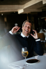 Handsome businessman dressed in the suit drinking wine. Businessman talking to the phone..