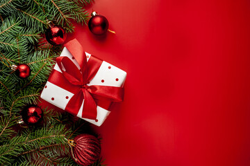 Christmas composition on a red background with a white gift box, with a red ribbon with fir...