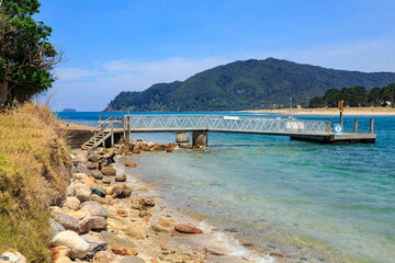 A jetty sticking out into the ocean at the coastal holiday town of Tairua on the Coromandel Peninsula, New Zealand