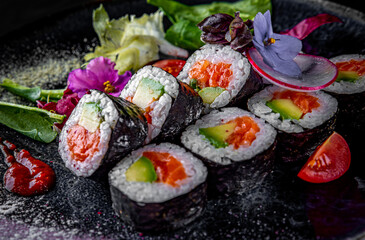 sushi roll with salmon, avocado in plate on black wooden table background