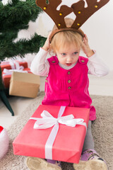 Child holding Christmas gift. Kid having fun at home. Xmas winter holiday concept