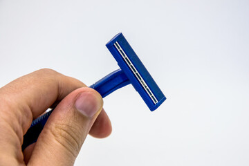 In his hand is a blue disposable razor on a white background.