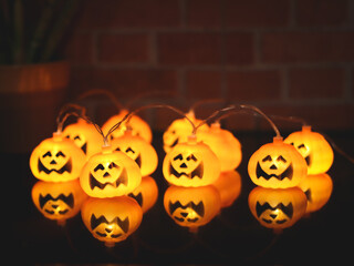 Halloween pumpkin string lights glowing with reflection on the table.. Halloween decoration concept.