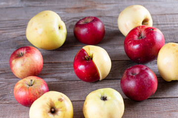 Ugly, juicy apples with defects on the skin on the wooden background. Funny, strange, imperfect fruits. Food waste and ugly food concept. Horizontal orientation composition