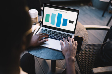 Cropped image of dark skinned male freelancer checking graphic charts and analytic browsing web page, top view of african american man millennial typing on laptop computer on online project