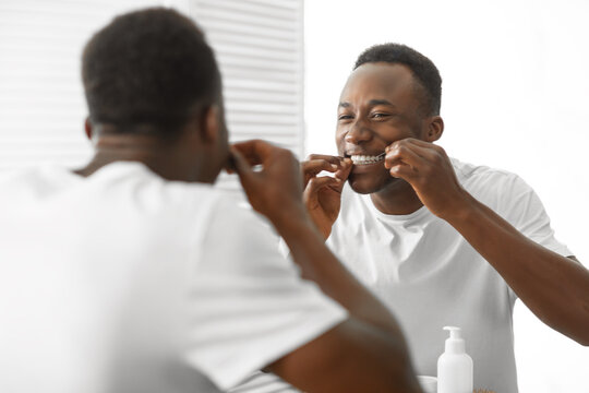 Black Man Cleaning Teeth With Floss In Bathroom At Home