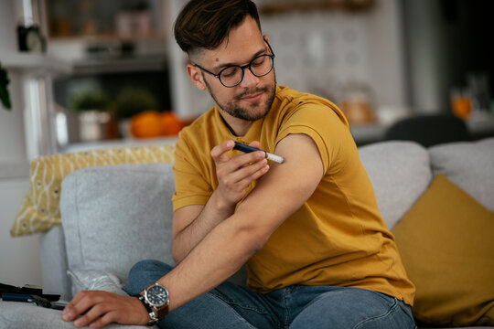 Young man giving himself an insulin shot at home..