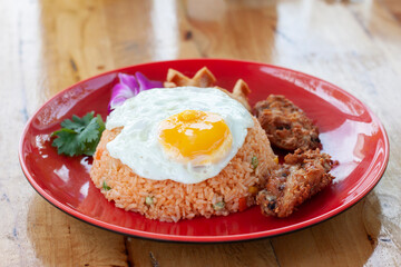 American fried rice in red plate on wooden table in the restaurant.