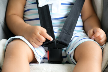 Baby sitting in car seat and pointed at safety belt locked protection.Adorable infant newborn for safe life from accident on road.