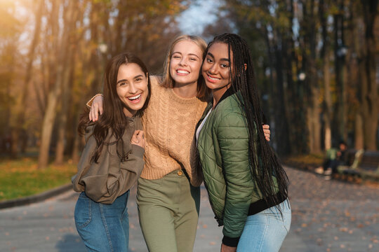 Trio of pretty teen girls posing in public park
