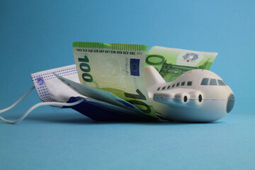 kleines Flugzeug mit Schutzmaske und Geld steht für Stornierungskosten bei Flugreisen 