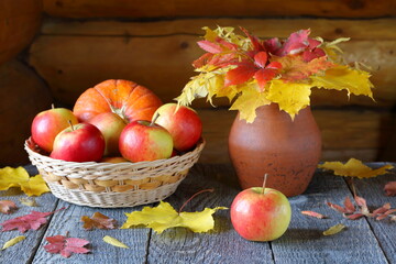 Fresh apples on a wooden table among autumn foliage.