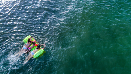 Fototapeta premium Mom and daughter are having fun in surf waves on the sea. Happy moments with children.