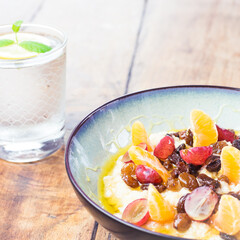 Healthy breakfast - oatmeal with tasty fruit and glass of water with lemon