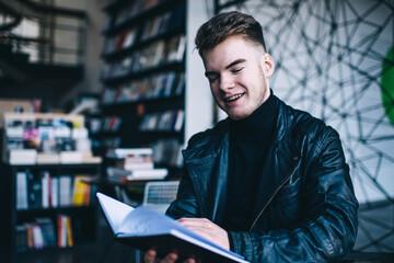Cheerful young man choosing books in bookstore