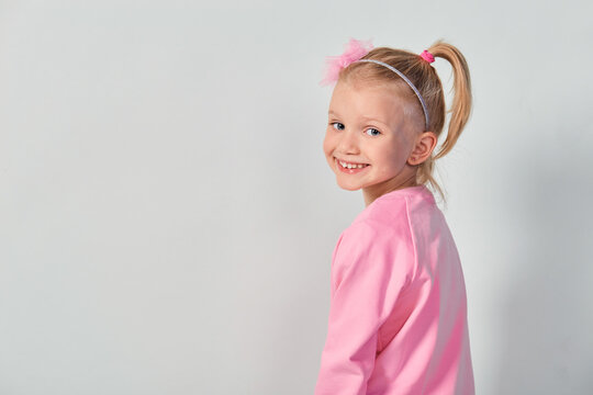 Cute girl 4-5 year old posing in studio in a pink sweatshirt