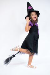 Cute girl standing in halloween witch costume over white background