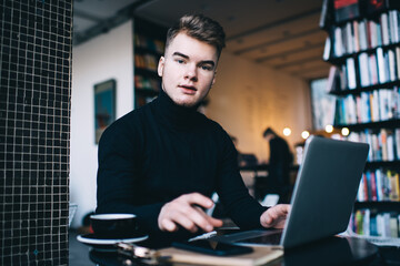 Young handsome man working on laptop in cafe