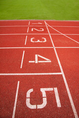 Athletic running track in a stadium with start point positions numbers one two, three, four five. No people.
