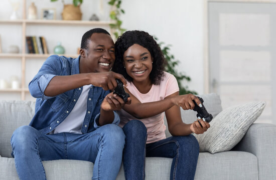 Joyful african american couple with joysticks at home
