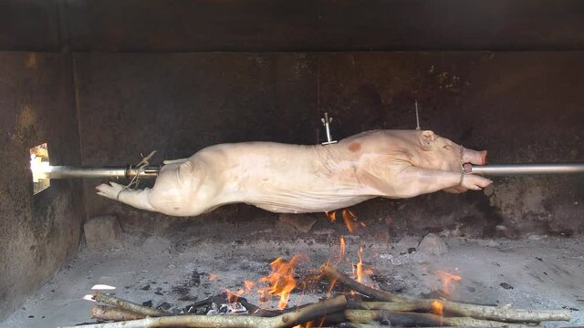Traditionally suckling pig on a rotating spit with fire and smoke