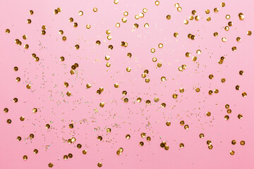 Pink background with gold sequins and shining paillettes. Suitable for backdrop for your design. Top view, copy space.