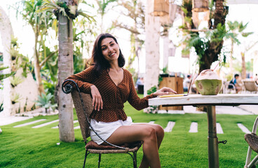 Happy young woman sitting with laptop on summer terrace