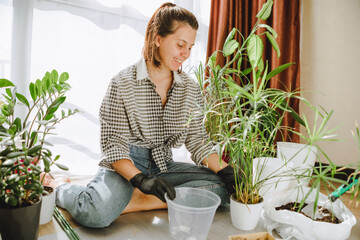 woman transplanting flowers in bigger pots at home