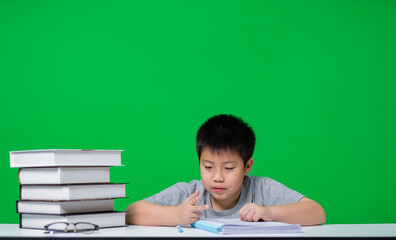 boy doing homework on green screen, child writing paper, education concept, back to school
