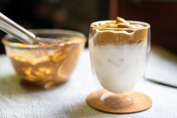 Dalgona Coffee; fluffy whipped coffee on milk. Coffee is a beverage made by whipping equal proportions of instant coffee, sugar and hot water until it becomes creamy. 