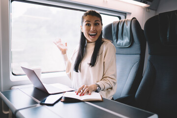 Fototapeta na wymiar Positive female passenger with laptop in train