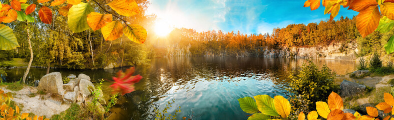 Die Farben vom Herbst um einen schönen See herum, mit Sonne und blauem Himmel, Panorama