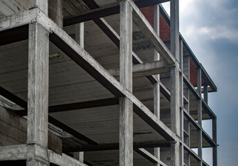 Reinforced concrete construction, load-bearing structure on cloudy sky background
